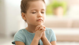 Cute little girl praying at home